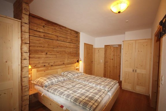 Hotelzimmer mit Bett und Altholztäfelung